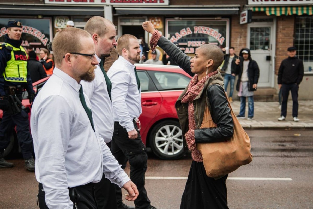 Femme seule poing levée devant néo-nazis