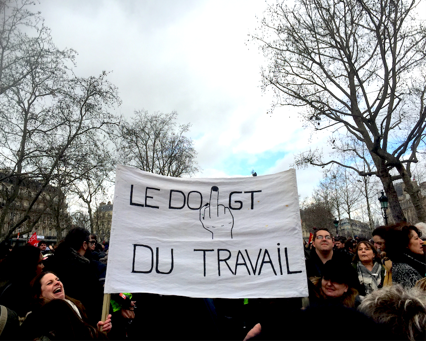 "Doigt du travail" sur une pancarte de la manif du 9 mars