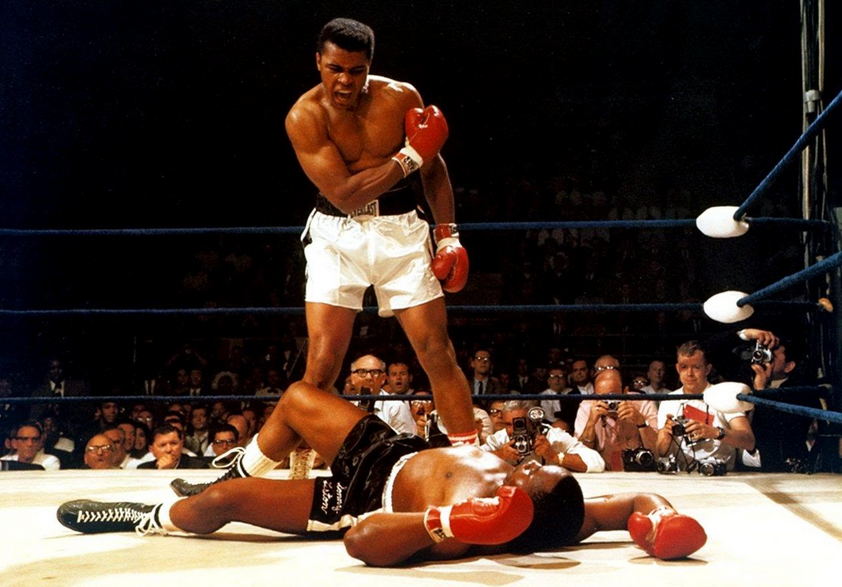 Mohamed Ali sur un ring de boxe devant un adversaire défait